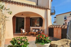 A cozy outdoor seating area with wooden furniture and potted plants. - [Mara] Elegant apartment in Sos Alinos (Orosei)