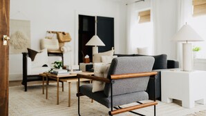 Un salon moderne avec un fauteuil gris, une table d’appoint blanche et un canapé noir.