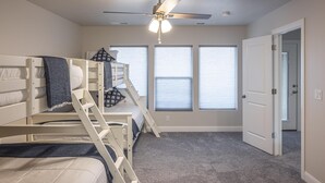 A bedroom with bunk beds, a ceiling fan, and a door leading to another room. - Poolside Plunge (St. George)