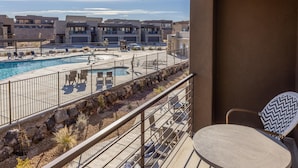 A balcony with a pool, outdoor furniture, and a view of a residential area. - Poolside Plunge (St. George)