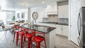 Una cocina moderna con armarios blancos, encimera de granito y refrigerador de acero inoxidable.