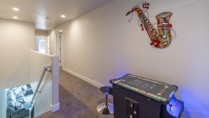 Un pasillo con una escalera, un adorno de saxofón en la pared y una mesa de billar.
