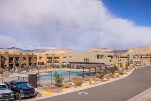 Um resort moderno com piscina, edifícios de vários andares e paisagem desértica ao fundo.