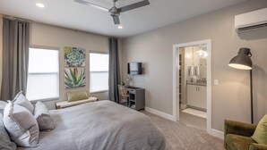 A bedroom with a bed, a desk, a chair, a TV, and a ceiling fan. - Cairn House 2 (St. George)