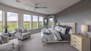 A bedroom with a large bed, two armchairs, a wooden nightstand, and a view of the outdoors. - Cairn House 2 (St. George)