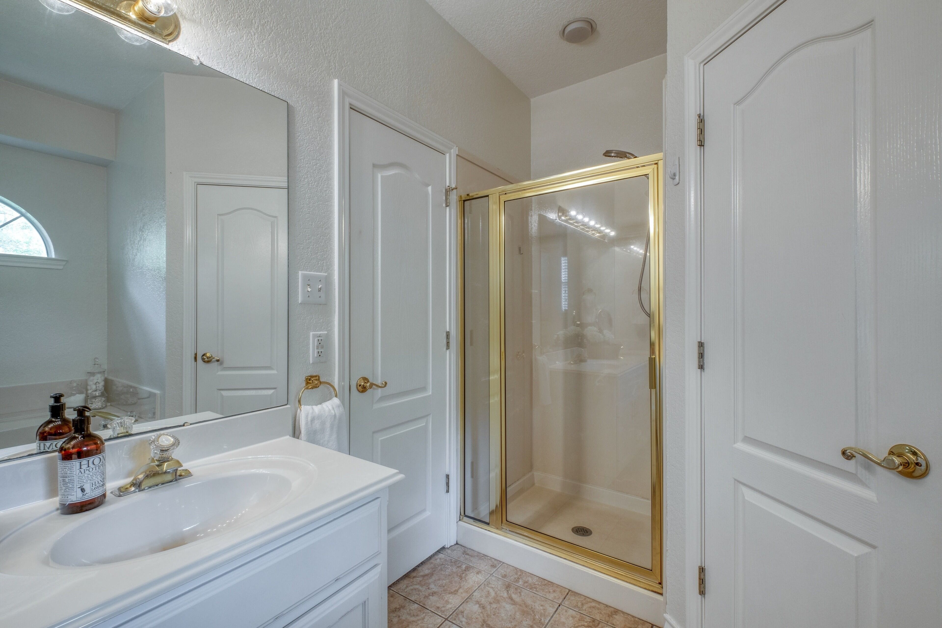 A bathroom with a white sink, a mirror, and a glass-enclosed shower.