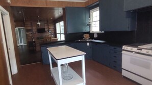 A kitchen with dark blue cabinets, a white stove, and a small white table. - Charming 1940s Home (Jefferson)