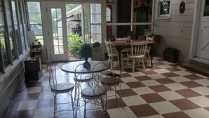 A covered patio with a checkered floor, a dining table with chairs, and a view of the outdoors. - Charming 1940s Home (Jefferson)