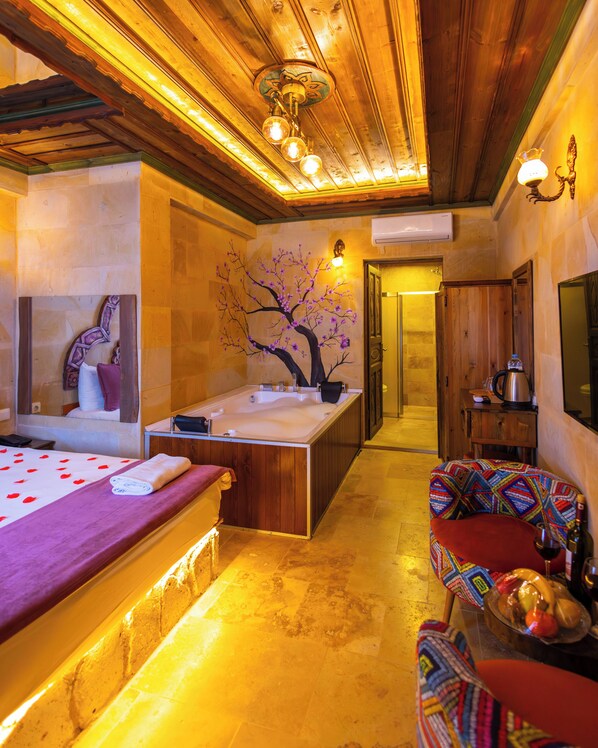 Un cuarto de spa con una bañera, una camilla de masaje, un sillón de colores y otra camilla de masaje montada en la pared.