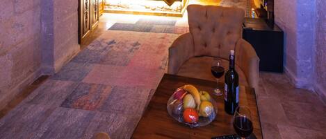 An underground room with a bed, a table with fruit and wine, and a sofa.