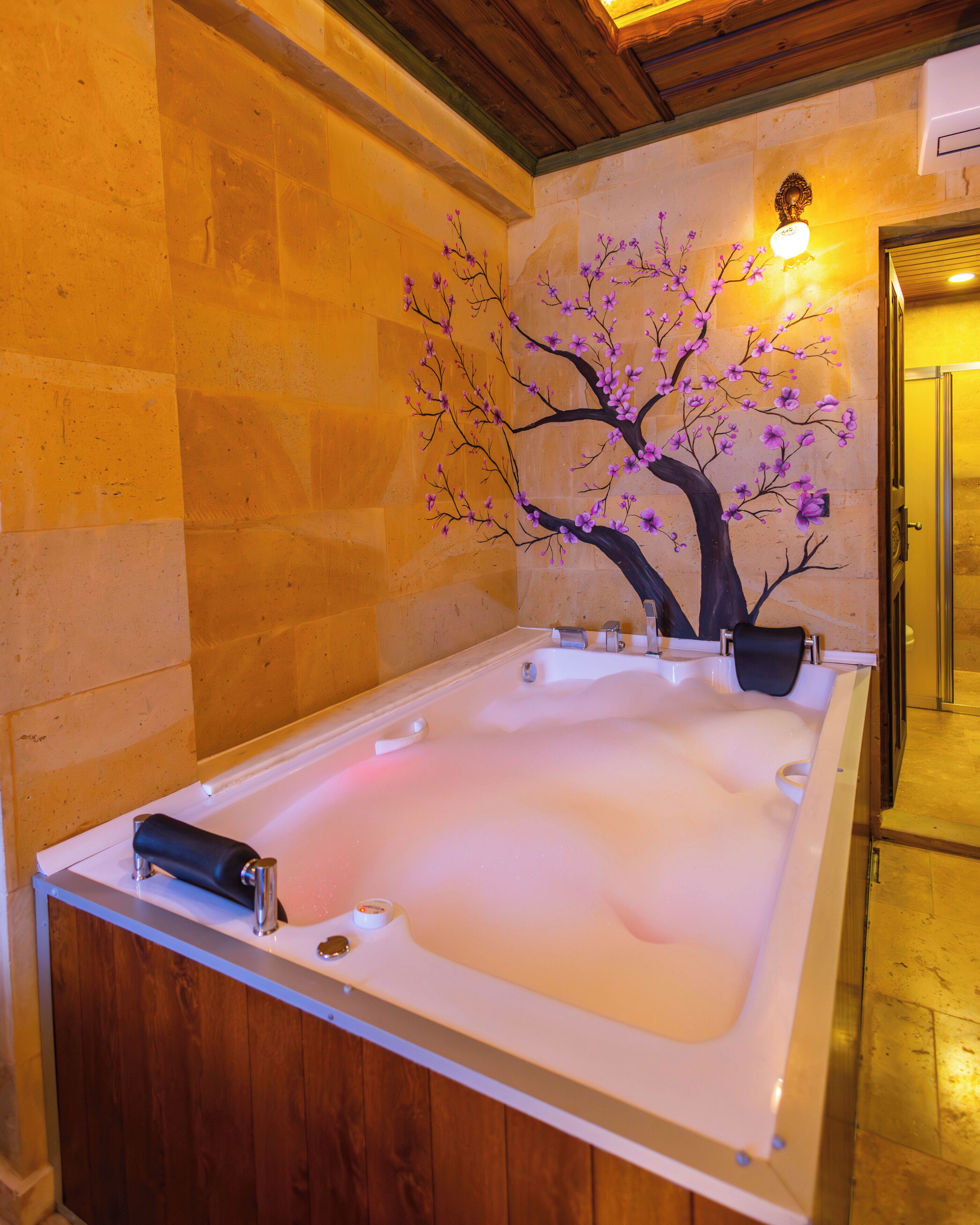 Un cuarto de spa con una bañera grande, una lámpara de pared y un techo de madera.