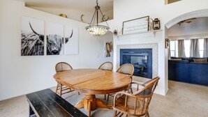 Uma área de jantar com mesa e cadeiras de madeira, um candelabro e obras de arte nas paredes.
