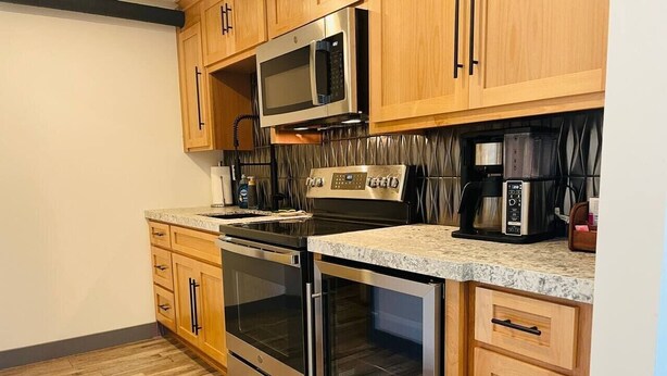 Una cocina con armarios de madera, electrodomésticos de acero inoxidable y encimera de granito.