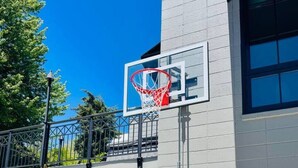 Un aro de baloncesto adosado a un edificio, con un cielo despejado al fondo.