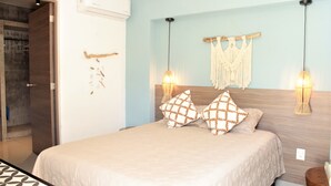 Un dormitorio con una cama, dos lámparas de pared, un tapiz de macramé y una puerta de madera.