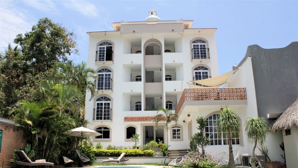 Un edificio blanco grande con varios balcones y una piscina.