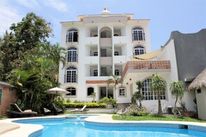 Un edificio blanco grande con varios balcones y una piscina.