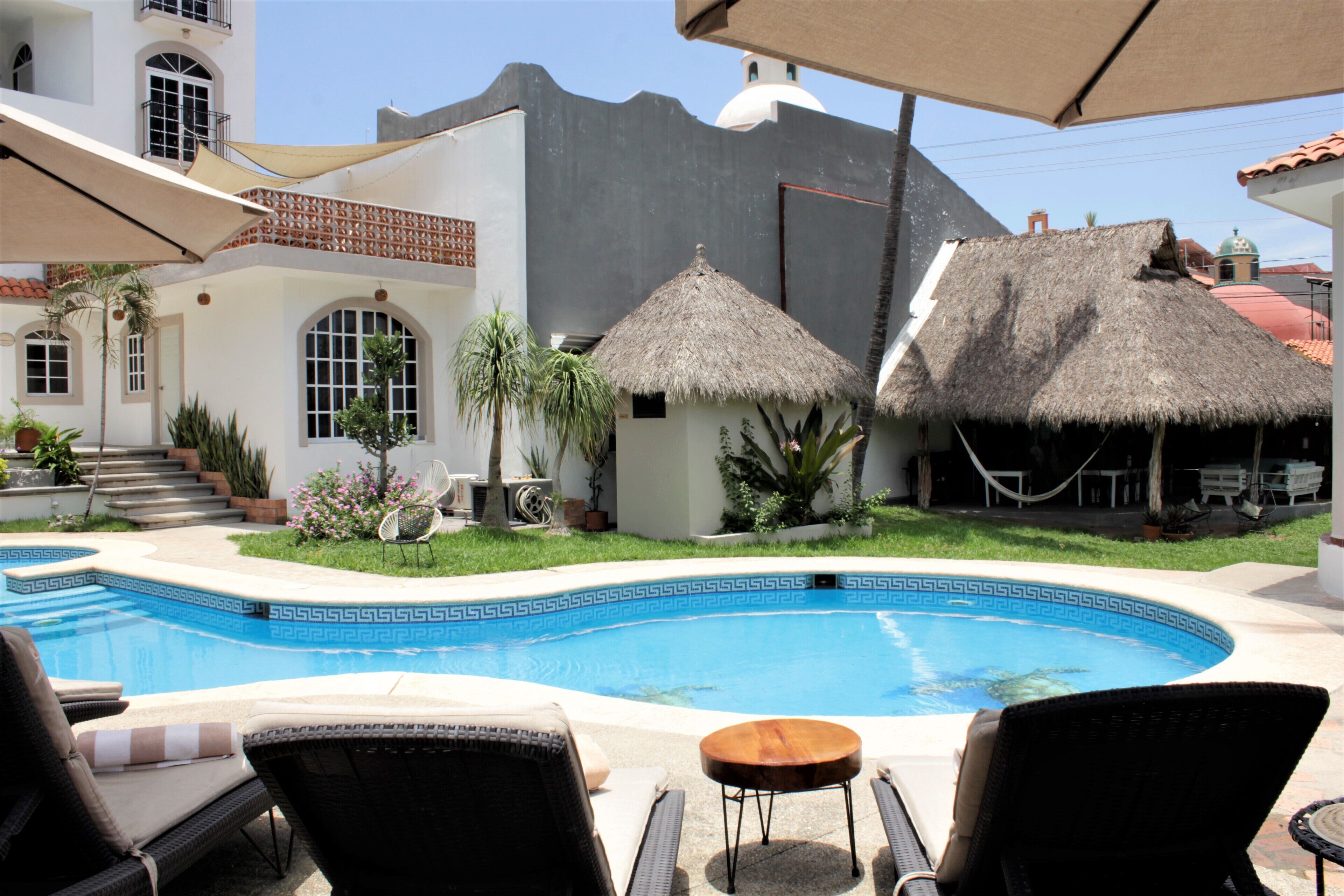 A swimming pool with lounge chairs and a thatched-roof structure.