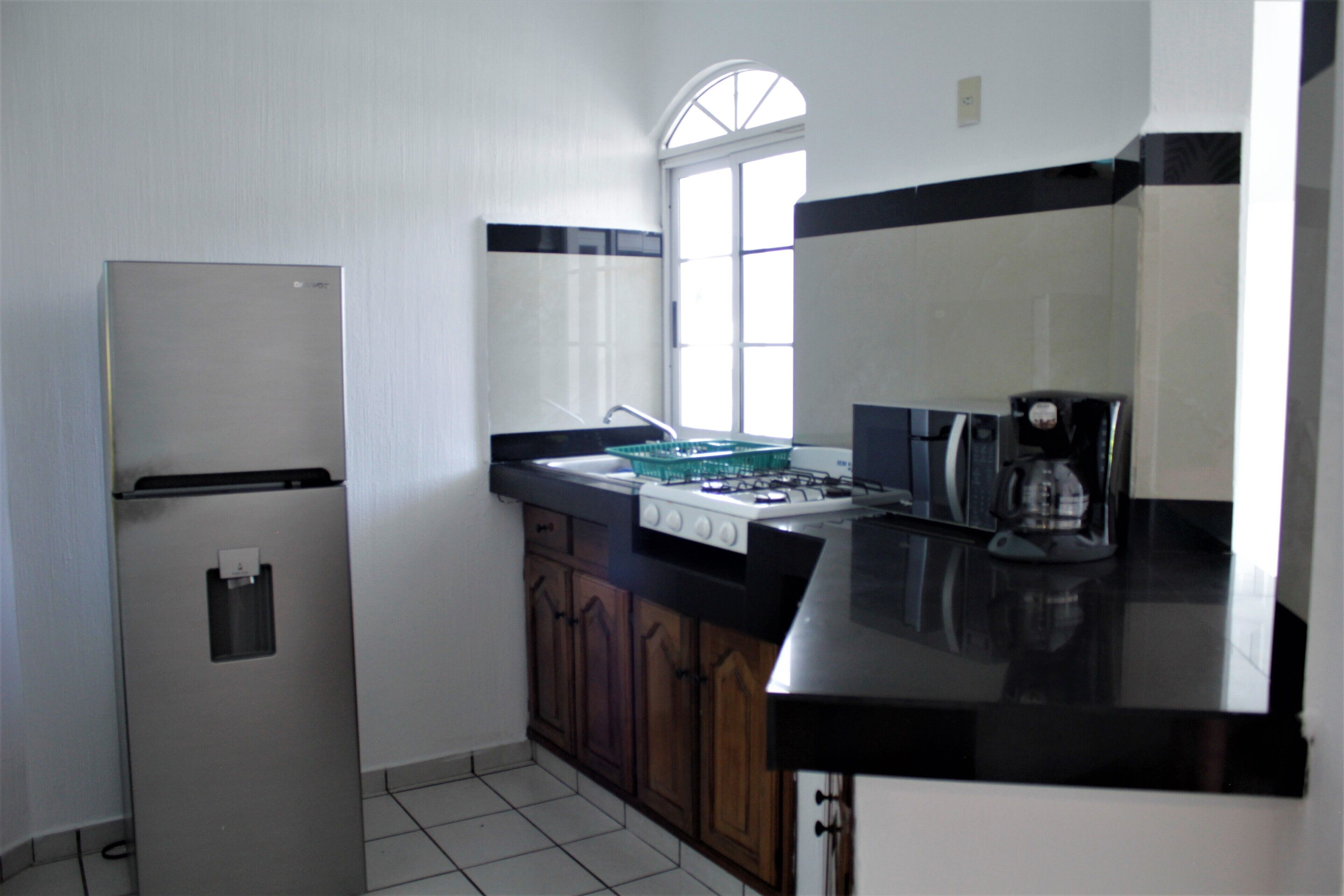 A kitchen with a refrigerator, stove, and coffee maker.