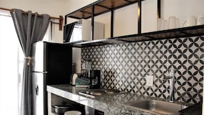 Una cocina con refrigerador de acero inoxidable, cafetera y pileta.