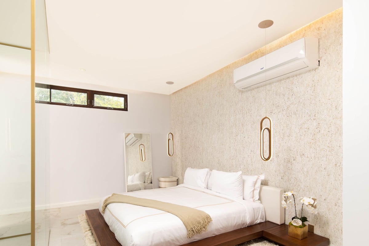 A modern bedroom with a large bed, a glass shower enclosure, and a marble floor.