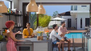 Una cocina moderna con una isla grande, luces colgantes y vistas a una piscina.