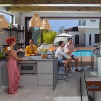Una cocina moderna con una isla grande, luces colgantes y vistas a una piscina.