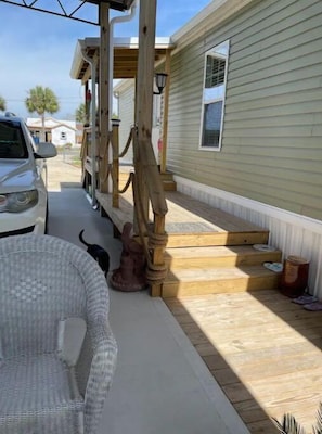 A residential area with a white car parked on the street, a wooden porch, and a small statue of a horse.