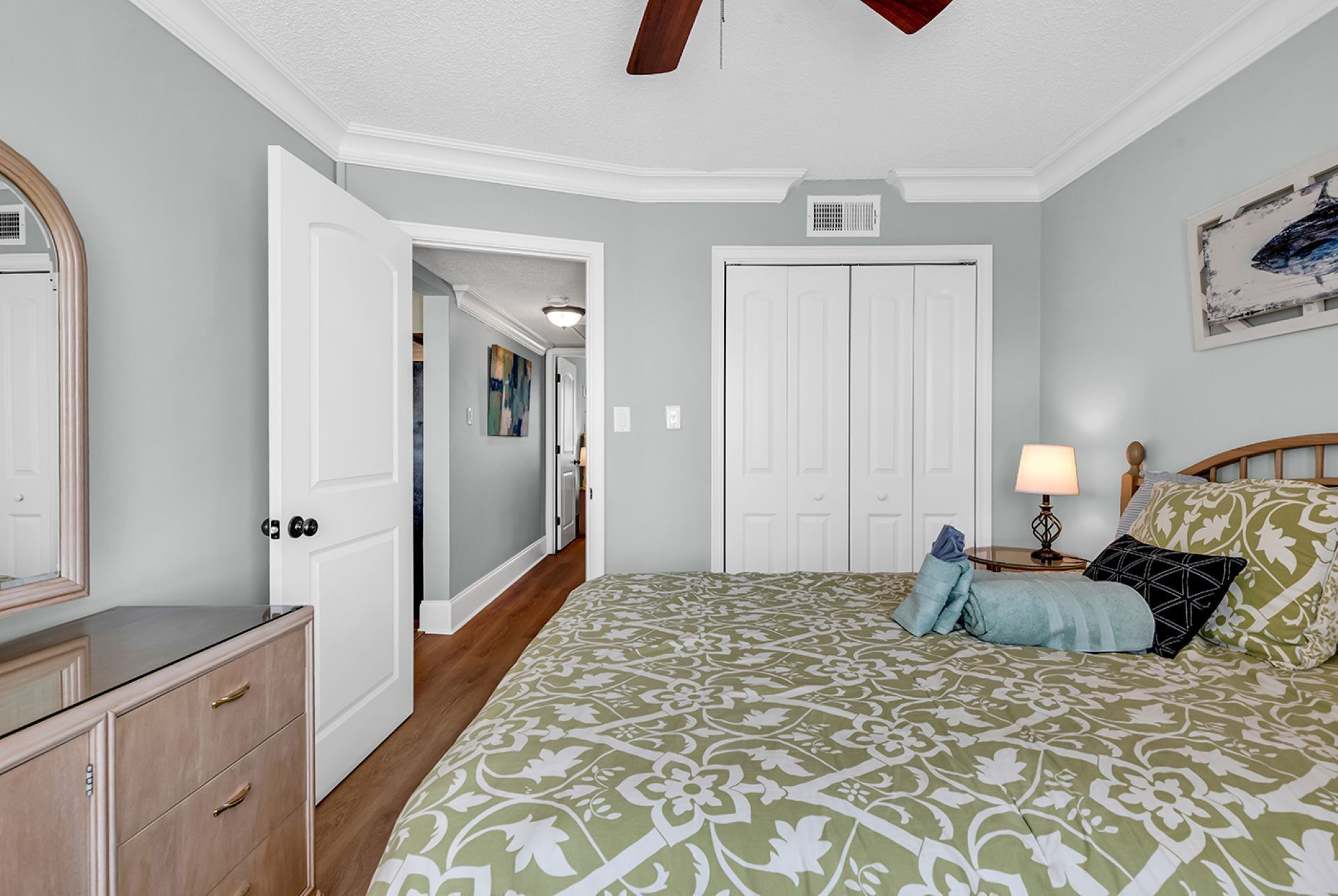 Un dormitorio con cama, cómoda y un pasillo que lleva a otra habitación.