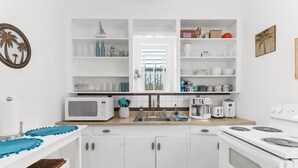 Une cuisine moderne avec des meubles blancs, un four à micro-ondes, une cuisinière et un évier.