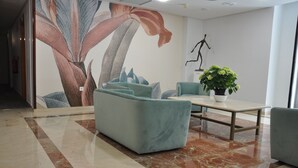 Un vestíbulo moderno con un gran mural floral, asientos cómodos, una mesita de centro y una planta en maceta.