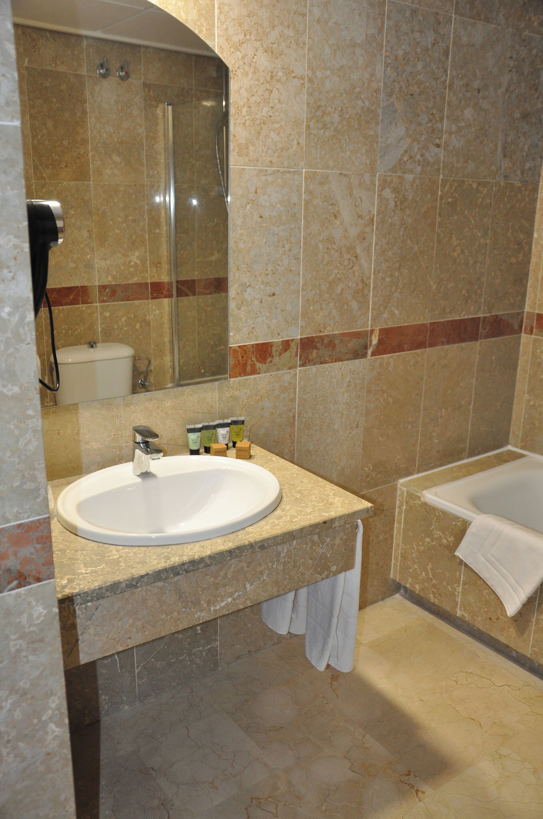 Un baño con lavamanos, espejo, ducha y bañera.