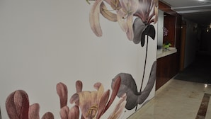 Un pasillo con un mural floral en la pared, un mostrador de recepción de madera y un piso de mármol.