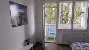 A bedroom with a bed, a chair, a small table, and a window. - Salimana charming apartman (Novi Sad)