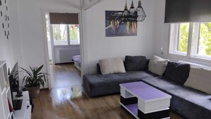 A modern living room with a sectional sofa, a coffee table, and a painting on the wall. - Salimana charming apartman (Novi Sad)
