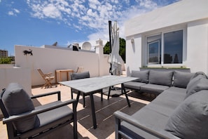 An outdoor patio with a table, chairs, and a sofa.