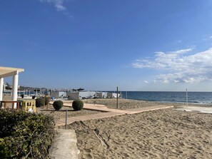 Une plage avec une promenade en bois menant à la mer, un espace de repos abrité et une vue sur l’océan.