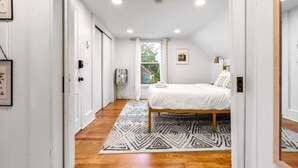 A bedroom with a bed, a patterned rug, and a window with curtains. - Peaceful 1BR | Reading Nook | Near Portland (Westbrook)