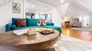 A modern loft apartment with a teal sofa, a wooden coffee table, and a dining area. - Peaceful 1BR | Reading Nook | Near Portland (Westbrook)