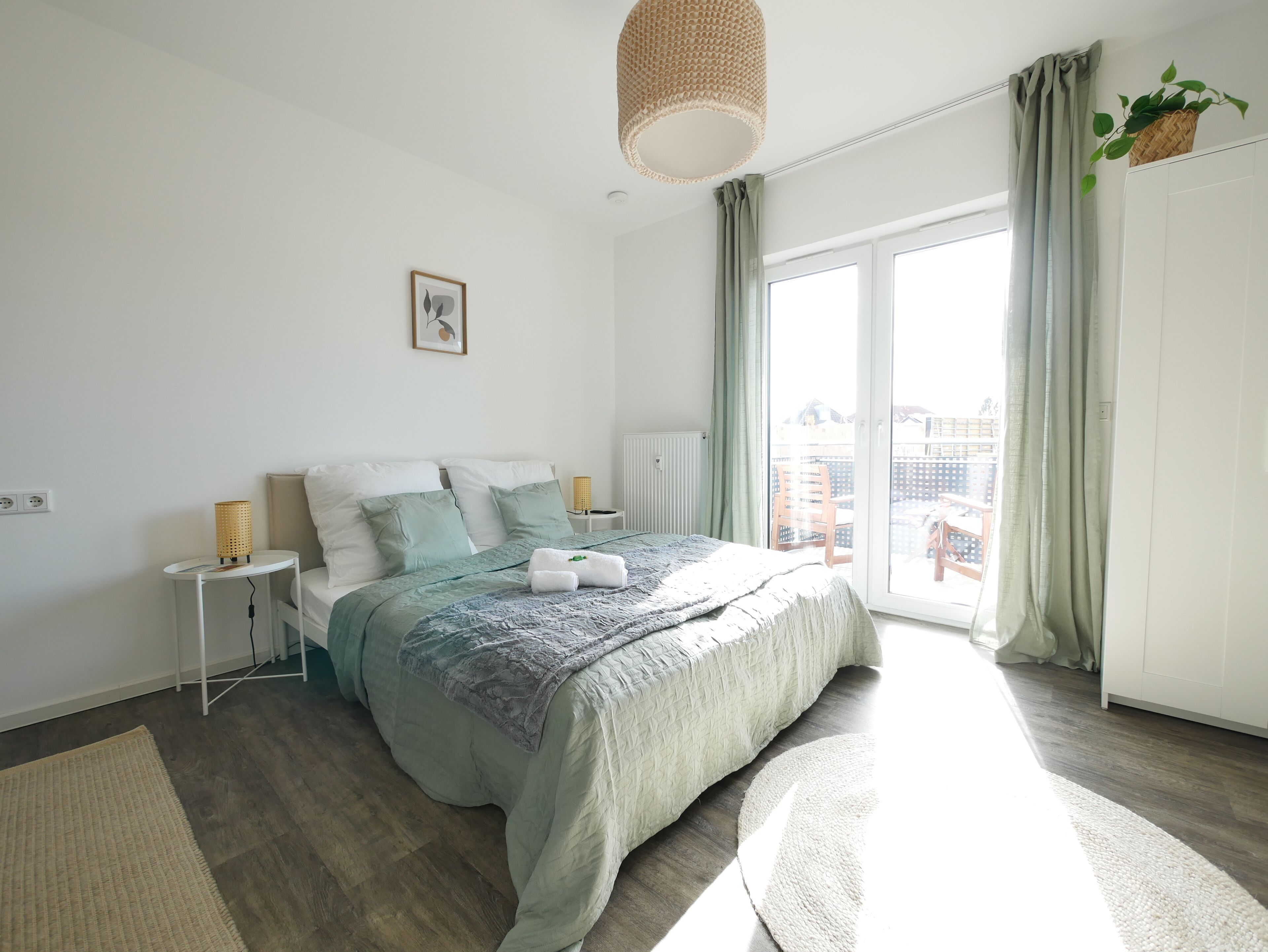 Un dormitorio moderno con una cama grande, una mesita de noche, una lámpara y vistas al exterior.