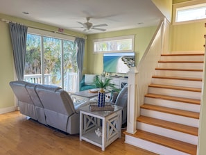 A living room with a sofa, a coffee table, a TV, and a staircase.