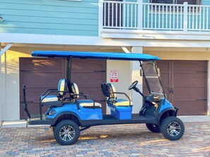 Une voiturette de golf est garée devant un bâtiment, à côté d’un panneau indiquant qu’il est interdit de se garer dans la rue.