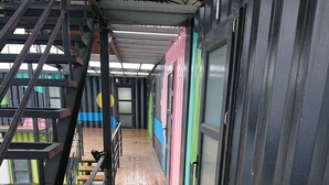 Ein überdachter Außenbereich mit Holzboden, Metallgeländern und bunten Wänden.