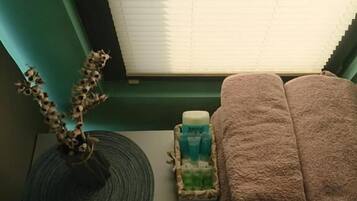 Une salle de bain avec un porte-serviettes, une plante décorative, une bouteille de shampoing et une serviette pliée.