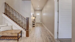 A hallway with a wooden staircase, a bench, and a door at the end. - Waterpark overlook with patio, firepit, pickleball (Santa Clara)