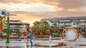 A water fountain with a colorful sculpture and a traditional building in the background. - Waterpark overlook with patio, firepit, pickleball (Santa Clara)