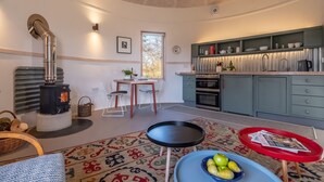 Een gezellige woonkamer met een open haard, een eethoek en een keuken met moderne apparatuur.