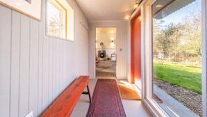 Een hal met een bank, een vloerkleed en een deur die leidt naar een kamer met een open haard.