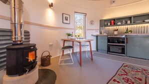 Een gezellige keuken met een houtkachel, een eettafel met stoelen en een inbouwoven.