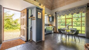 A spacious kitchen with a dining area, large windows, and a view of greenery. - Ultimate Constable Country retreat -The Pump House (Colchester)